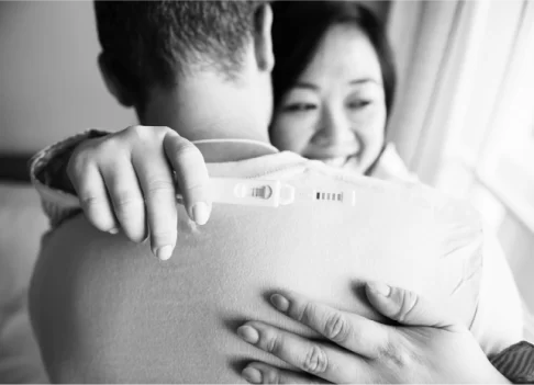 Couple hugging and celebrating a positive pregnancy test.